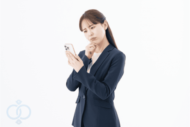 スマートフォンを見ながら悩んでいる女性。調査費用や依頼先について検討している様子を表現した画像