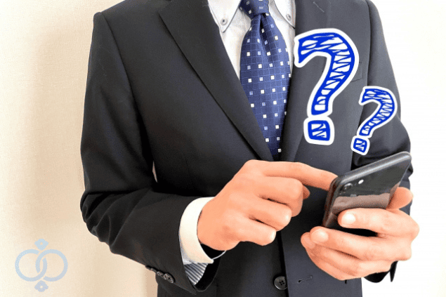 スマートフォンを操作しながら疑問を抱えているスーツ姿の男性。LINEから電話番号を調べられるのか困惑している様子を表現したイメージ。