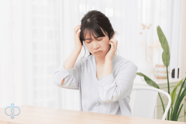 頭を抱えて悩む若い女性の画像。LINEしか知らない相手と連絡が取れなくなり、電話番号を調べたいと感じている複雑な心情を表現。