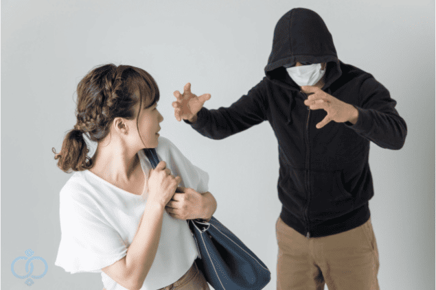 女性に対して威圧的に迫るフード姿の男性。つきまといやストーカー行為による不安を表現したイメージ写真。