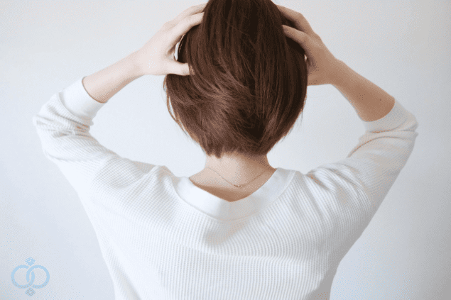 ストレスや悩みを抱え、頭を抱える女性の後ろ姿。精神的に追い詰められた妻の家出原因を象徴的に表現したイメージ。