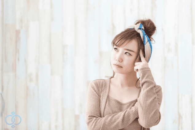 指をこめかみに当てて考える女性。既婚者の恋人と別れられない理由を自問している様子。