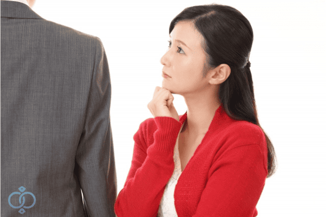 男性を見上げるように不信感を抱く女性。彼氏の言動に違和感を覚え、既婚者かもしれないと疑い始めた様子を表現。