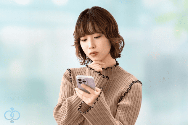 スマホを見つめて思案する女性。恋人の「離婚する」という言葉に不安を感じている様子。