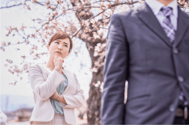 背を向けて歩く男性を見つめる女性の画像。恋人の言葉を信じきれず、行動から本心を見極めようとしている場面を表現。