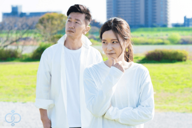 前方で考え込む女性と、後ろで無表情に立つ男性の写真。彼氏が既婚者かもしれないと疑い始めたきっかけを表現した画像。