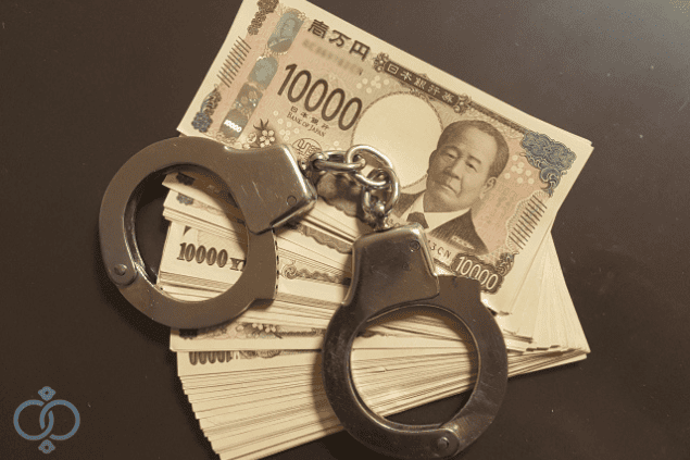 現金の上に置かれた手錠の画像。金銭トラブルが詐欺として刑事事件化するリスクを表現。