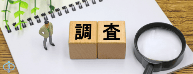 ノートの上に調査と書かれた木のブロックと虫眼鏡、探偵らしき人形の画像。