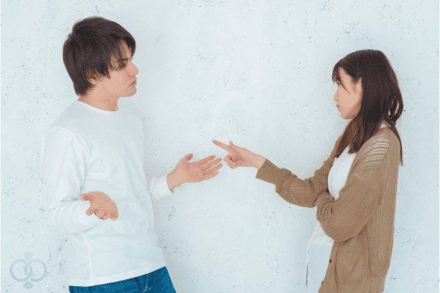 男性の言い訳に対して、指を差して問い詰める女性。既婚者の彼氏がつく典型的な嘘に対する疑念と対立の様子を表現。