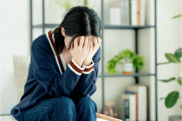顔を両手で覆って後悔する女性。既婚者の言葉を信じたことで傷ついた過去を思い返している様子。