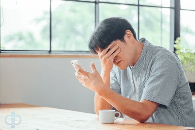 スマホを見ながら頭を抱える男性の画像。風俗嬢にお金を貸した後に連絡が取れなくなり、困惑している様子を表現。