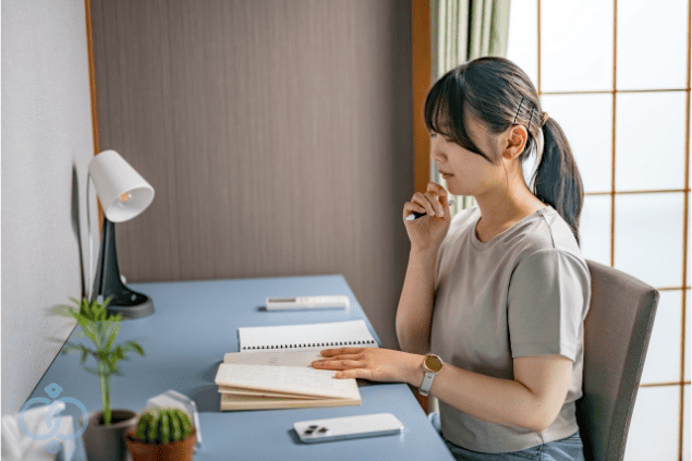 ノートに向き合って考え込む女性。恋人と別れられず悩む中で、自分の気持ちを整理しようとしている様子。