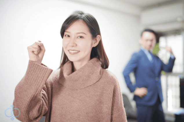 安心した表情でガッツポーズをする女性と、それを見守るスーツ姿の男性。探偵の調査によってストーカー問題が解決し、前向きな気持ちを取り戻した依頼者をイメージした事例セクション画像。