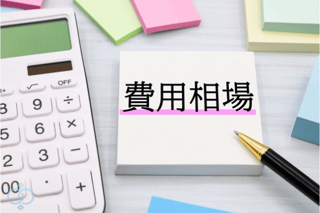 費用相場と書かれたメモ帳の横に電卓とペンが置かれた写真。探偵へのストーカー調査を依頼する前に費用を確認しようとする読者のイメージを表現したセクション画像。