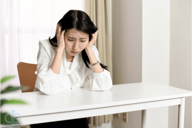 頭を抱えて悩む女性。既婚者の彼氏との別れを決断できず、気持ちの整理がつかずに苦しんでいる様子。