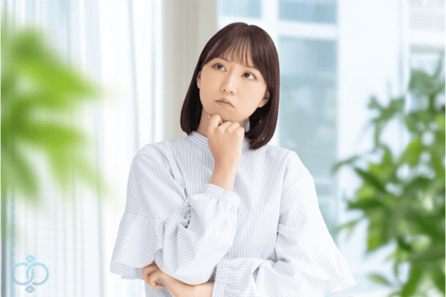 口元に手を当てて考え込む女性の画像。彼氏が既婚者かもしれないと疑い始めた女性の思考や整理の様子を表現している。