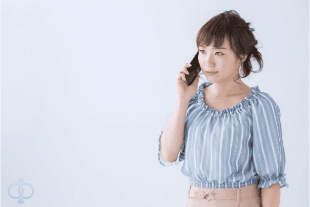 スマホで話しながら軽く微笑む女性の画像。風俗嬢がお金を返してこない時によくある言い訳やその背景をイメージ。