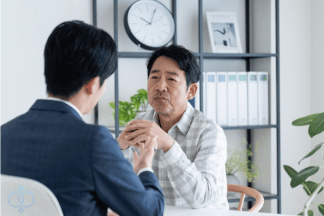探偵事務所で男性相談者が真剣な表情で話を聞いている様子の画像。金銭トラブルに関する無料相談のイメージを表現。