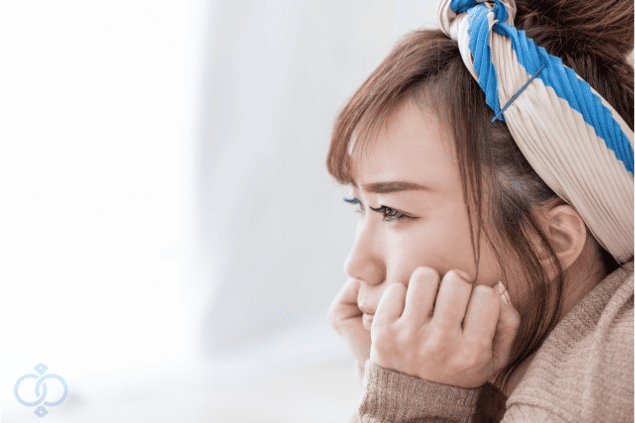 不安そうに頬杖をついて遠くを見つめる女性の横顔。夫の素行調査を考えるべきタイミングと理由を示すイメージ画像。
