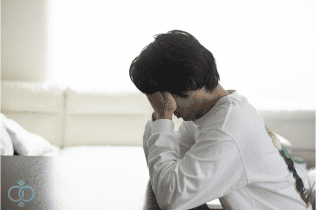 顔を覆ってうつむき、返済を約束されたのに音信不通となり不安と後悔に悩む男性の画像。