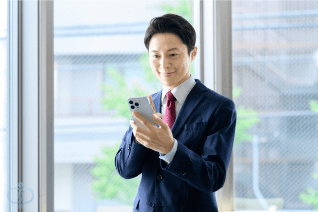 スマホを見ながら嬉しそうに微笑む男性の画像。風俗嬢の結婚詐欺で被害者が甘い言葉を信じてしまい、巧妙な手口に気づかない現実を表現。
