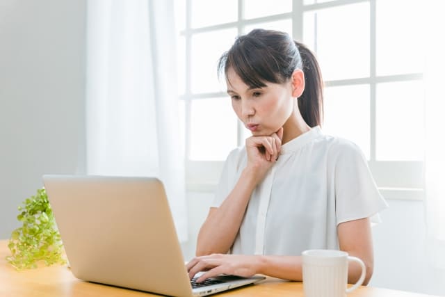 娘の結婚相手について調べようと、パソコンを使って真剣に検索する母親のイメージ