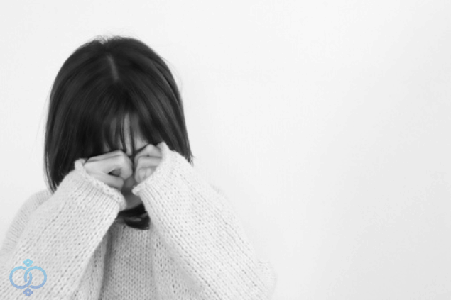 若い女性が手を顔にあてて泣いているイメージ写真