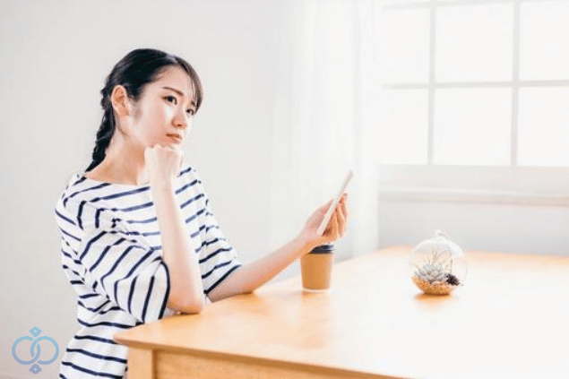 携帯を持ち考える若い女性のイメージ画像