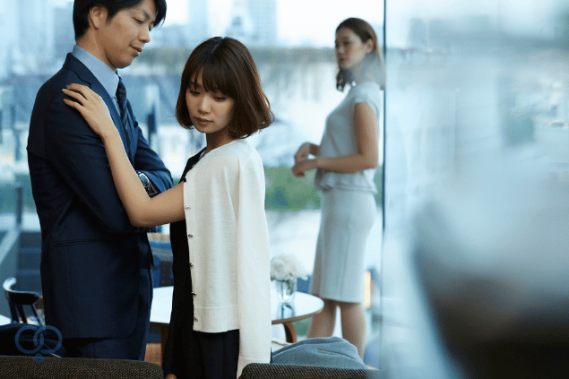 社内で男女が親密な関係を見つめる女性