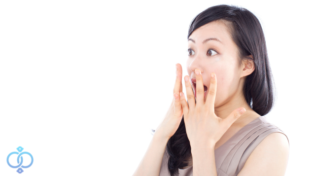 口に手を当てて驚く女性