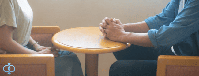 テーブル越しに向き合う男女。冷静な話し合いのイメージ画像