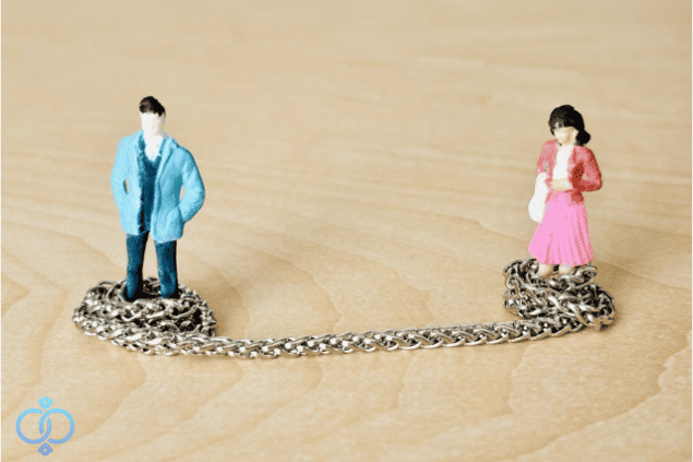 鎖でつながれた男女の人形。関係がいつまでも断ち切れない様子をイメージした画像