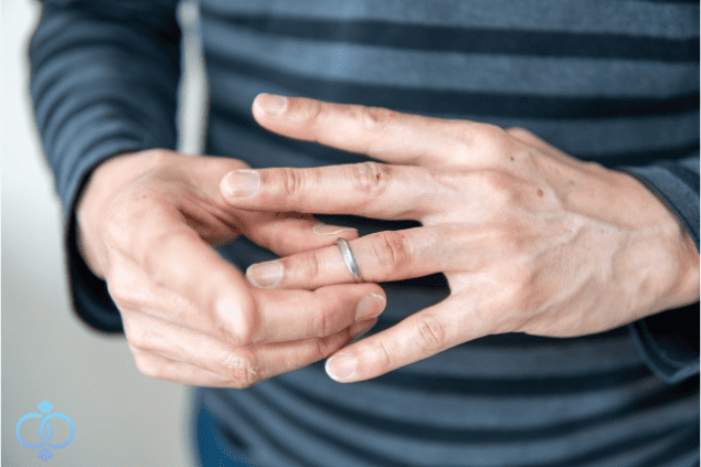 結婚指輪を外そうとする男性の手元の画像。