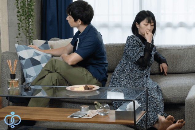 背を向けてソファーに座る男女。仲の悪そうな夫婦のイメージ画像