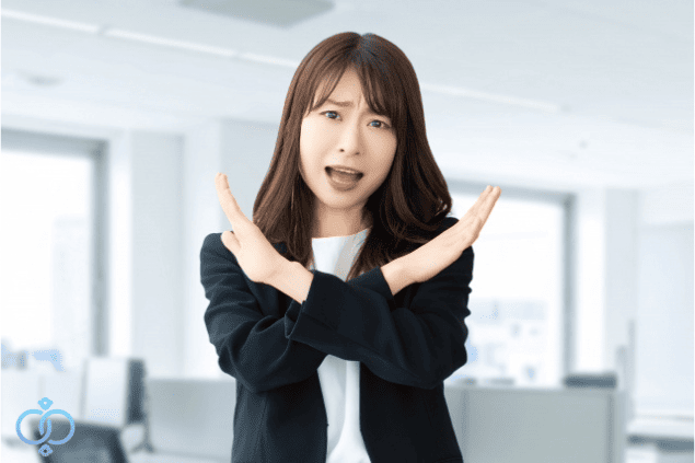 両手でバツ印を作るスールを着た女性の写真。浮気発覚後にやってはいけない対応を警告するイメージ画像