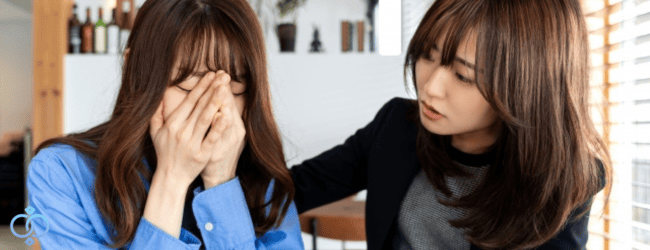 泣いている女性に寄り添いながら話を聞く女性の写真。信頼できる第三者に話すことをイメージした画像