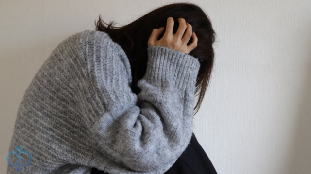 頭を抱えて悩んでいる女性