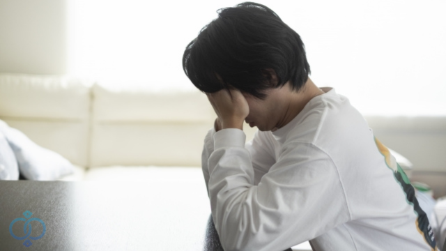 顔に手を当て落ち込む男性