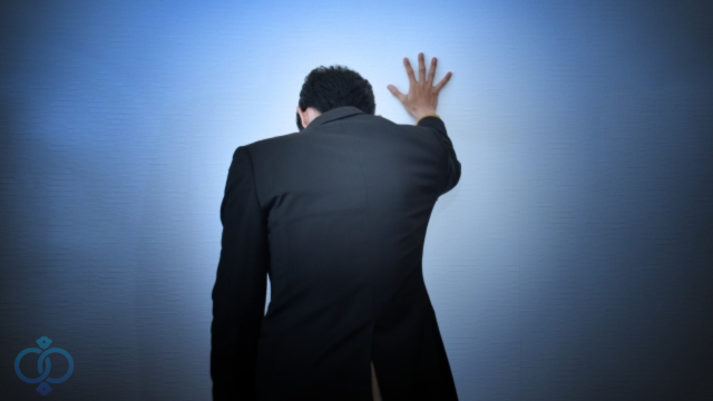 壁に手を付き落ち込む男性