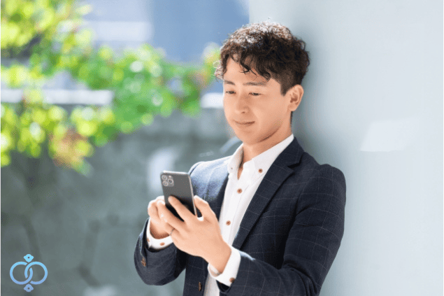 スマートフォンを手に持ち明るい表情の男性。自分の気持ちに整理がついた様子をイメージ
