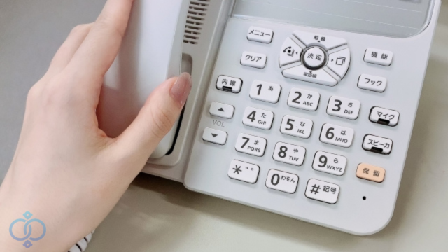 電話の受話器を持つ女性の手