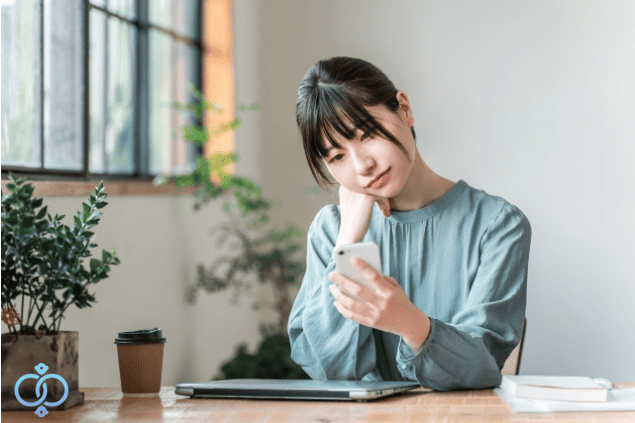 悩みながら携帯を見る女性。既婚者女性が風俗で働き始める様子をイメージした画像