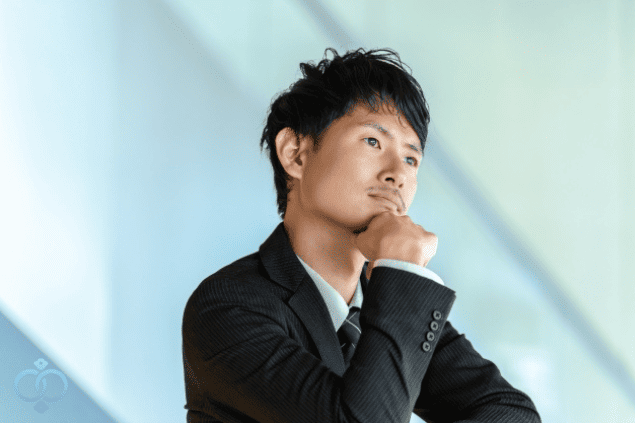 スーツの男性が顎に手を当て考える様子。
彼女と連絡が取れない理由を考える男性をイメージした画像