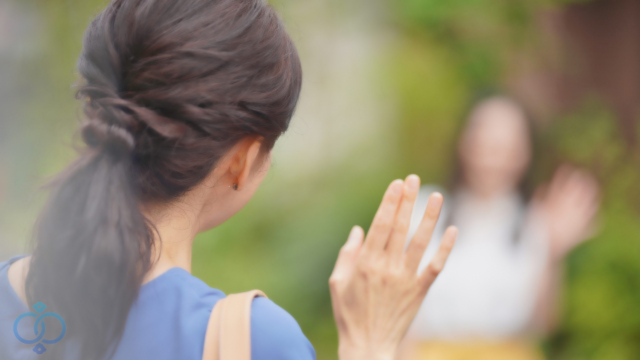 娘に手を振る母親の後ろ姿