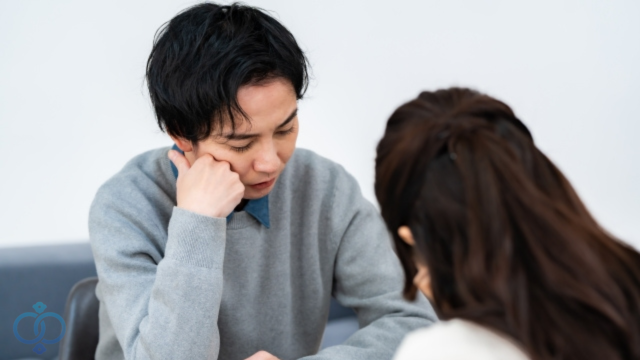 話し合いうつむくカップル