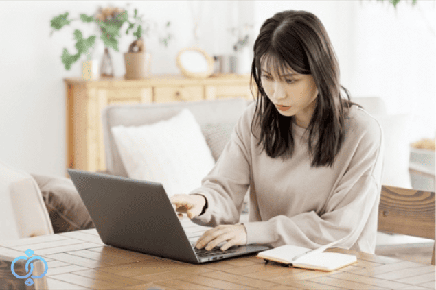 自宅でパソコンを使いながらメモを取り、失踪した家族の情報を調べている様子。自分でできる捜索方法をイメージした場面。