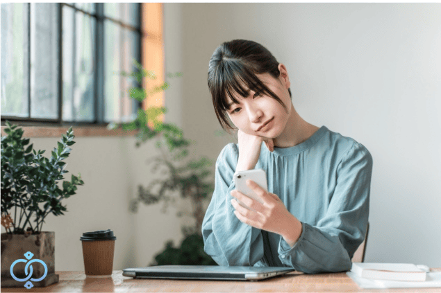 スマホを見ながら探偵と警察のどちらに相談すべきか悩む女性のイメージ
