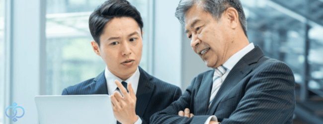 企業調査の目的と必要性について、パソコンを見ながら企業リスクや判断材料を確認するビジネス担当者たちの様子。