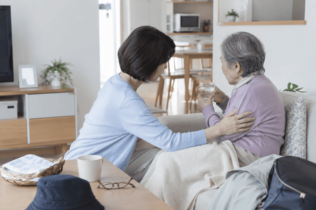 見つかった認知症の高齢家族に水を渡し、体調を気づかう女性