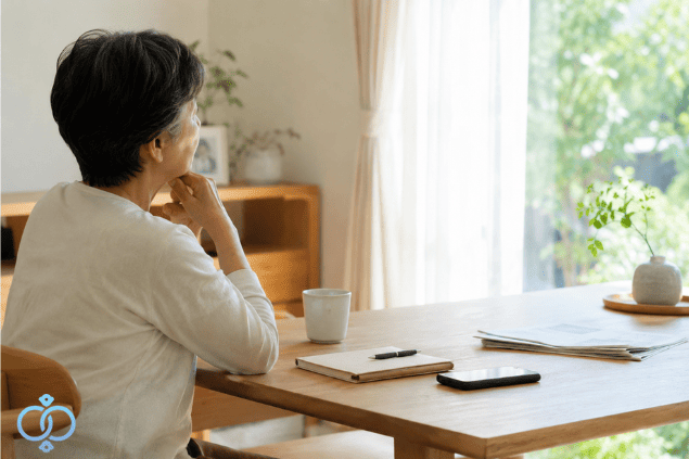 息子と連絡が取れない不安を抱えながら、窓辺で次にできることを落ち着いて考える親世代の女性